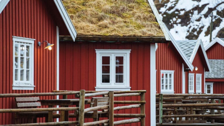 Rood Scandinavisch houten huis met witte kozijnen en een grasdak